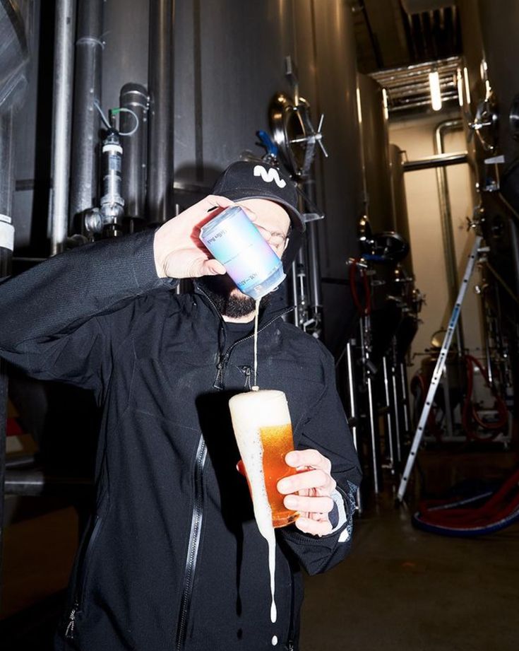 A pint poured over the top in a brewery cellar, foam spilling down the glass